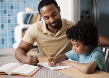 Father helping son (7-9) with homework --- Image by © Tim Pannell/Corbis